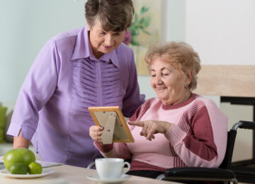 A volunteer from JSSA's Transitions program offers companionship to an elderly woman in a facility