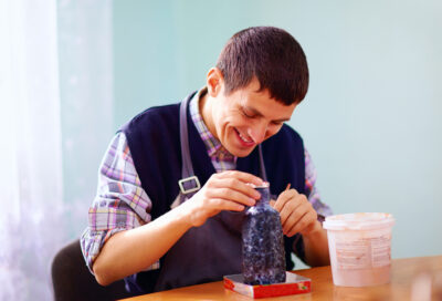 Young adult with special needs painting pottery with JSSA's Out and About social club