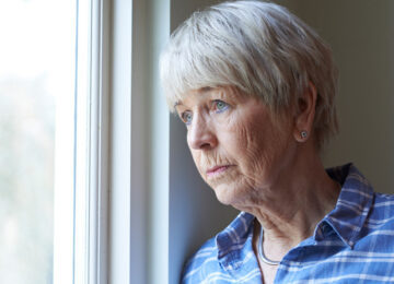 eldelry woman sadly looking out window