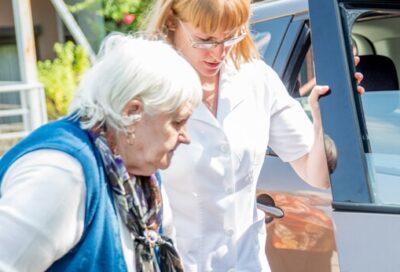 nurse helping woman into car