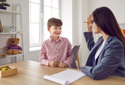 A smiling young boy listing to a child psychologist.