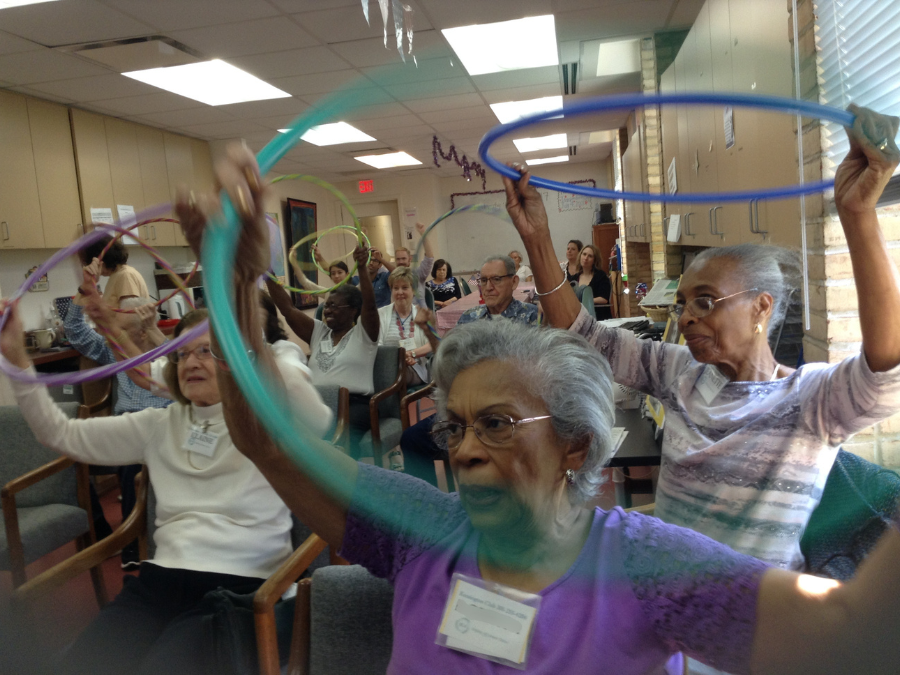 group of seniors do seated activity with hula hoops