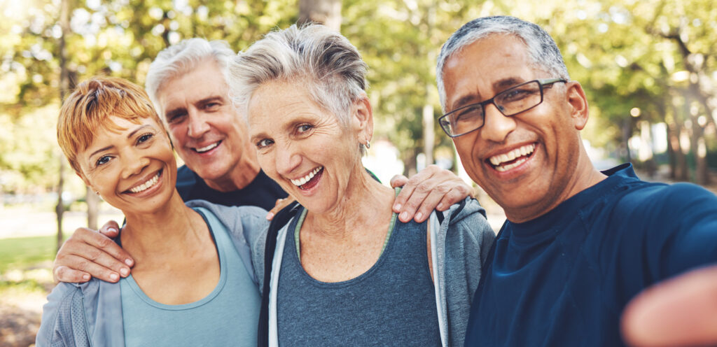 Four mature adults smile in outdoor setting
