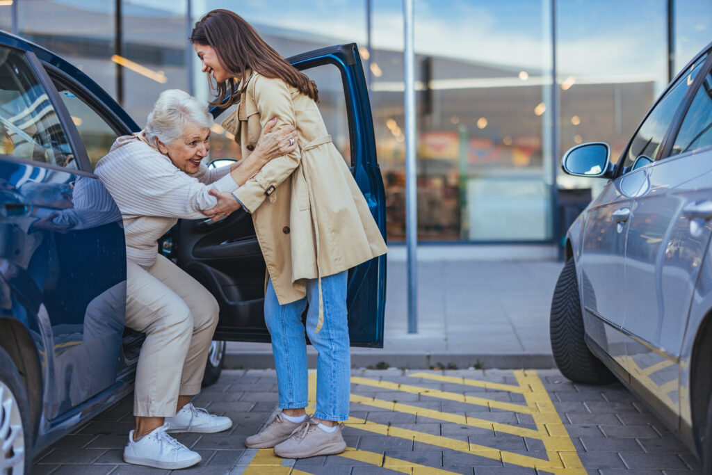 Young woman helps older woman out of car