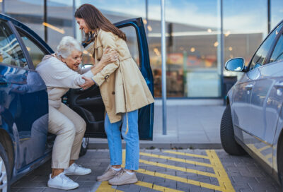 Young woman helps older woman out of car