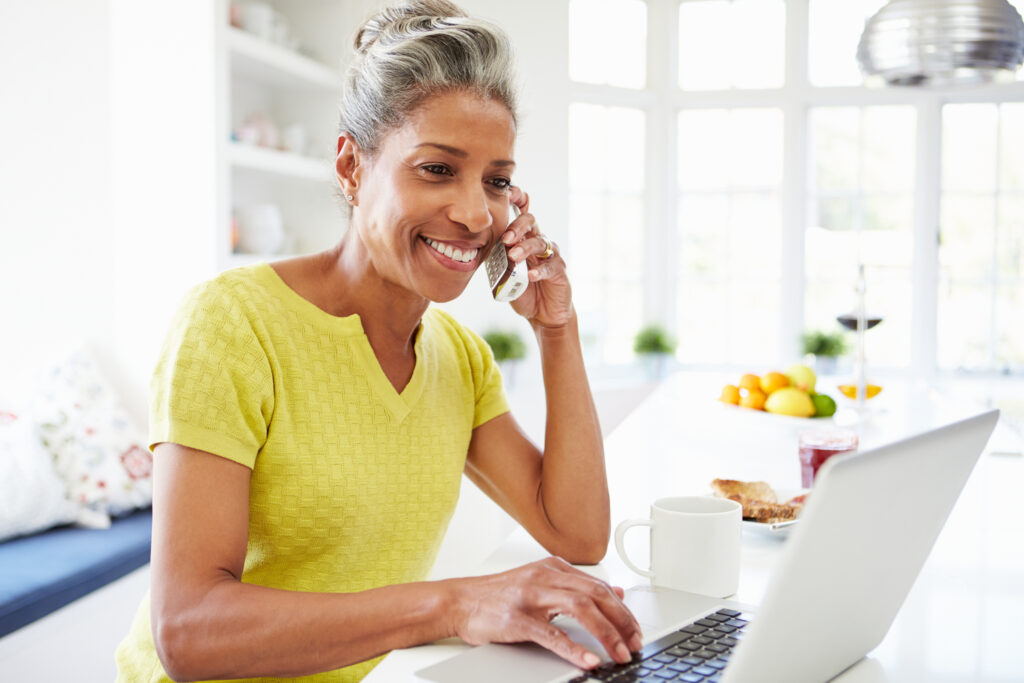 woman talking on phone while using a laptop