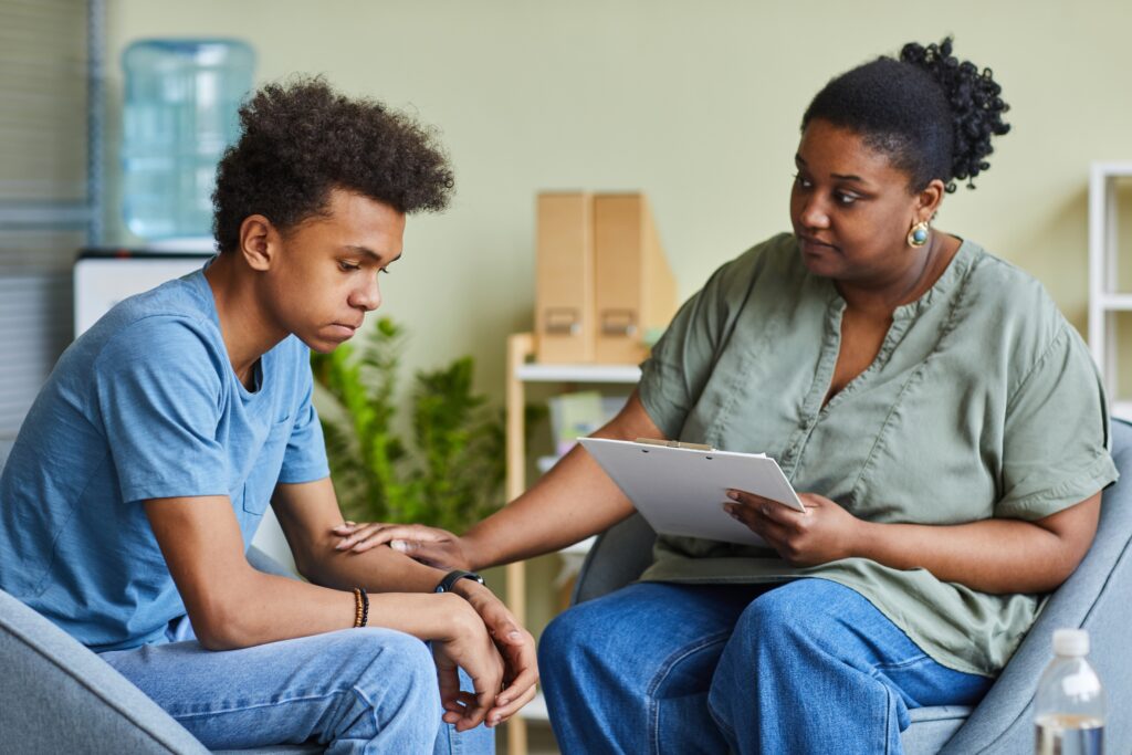 A counselor comforts a sad teenage boy.