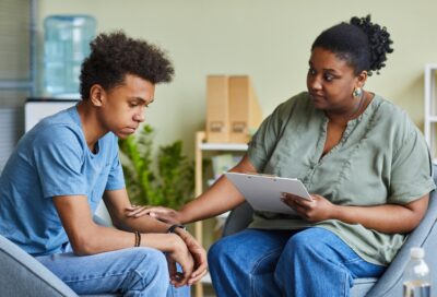 A counselor comforts a sad teenage boy.